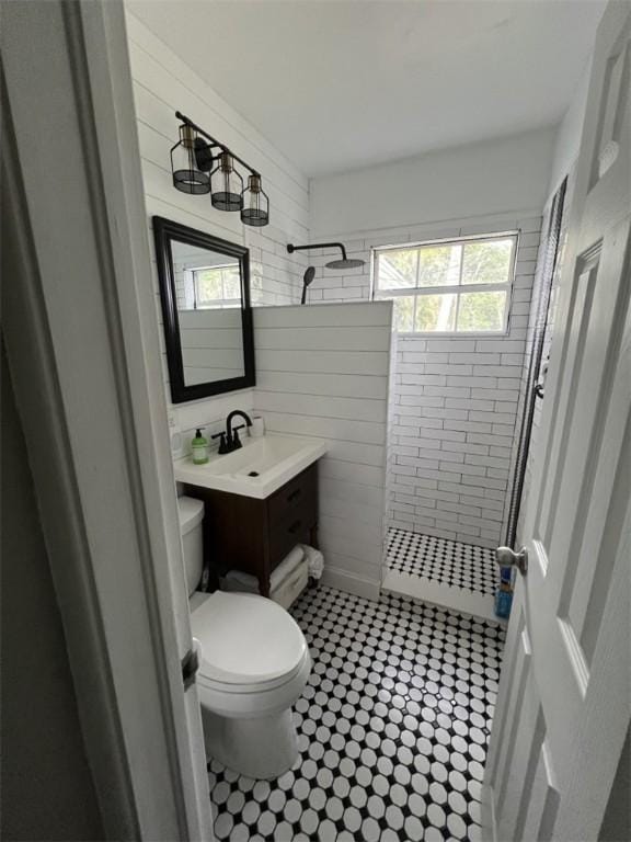 bathroom featuring a tile shower, toilet, and vanity