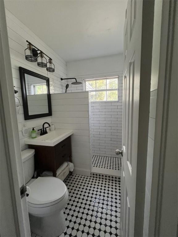 bathroom with tiled shower, toilet, vanity, and tile patterned floors