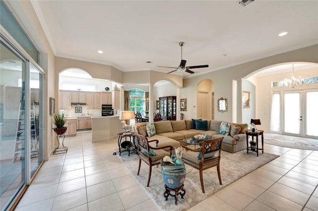 living room with ceiling fan with notable chandelier, light tile patterned floors, and crown molding