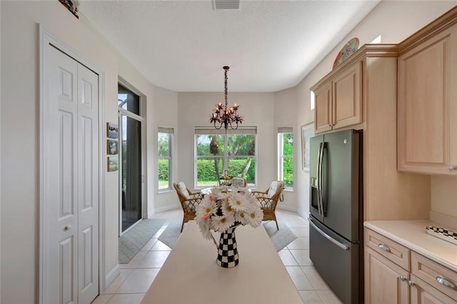 tiled dining area with a textured ceiling and a notable chandelier