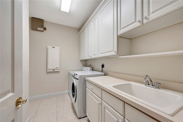 laundry room with cabinets, a textured ceiling, sink, light tile patterned floors, and washing machine and dryer