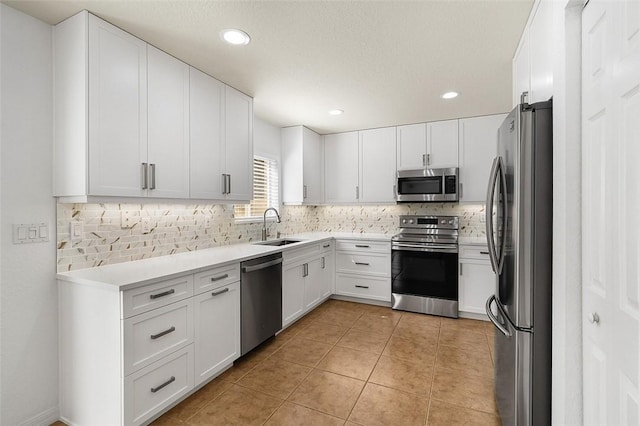 kitchen with light tile patterned floors, light countertops, appliances with stainless steel finishes, white cabinets, and a sink