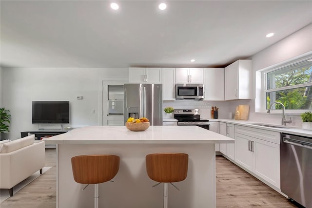 kitchen featuring a breakfast bar area, stainless steel appliances, tasteful backsplash, open floor plan, and a sink