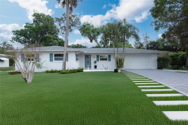 single story home featuring a front lawn, decorative driveway, an attached garage, and stucco siding