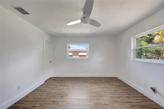 unfurnished room with baseboards, plenty of natural light, visible vents, and wood finished floors