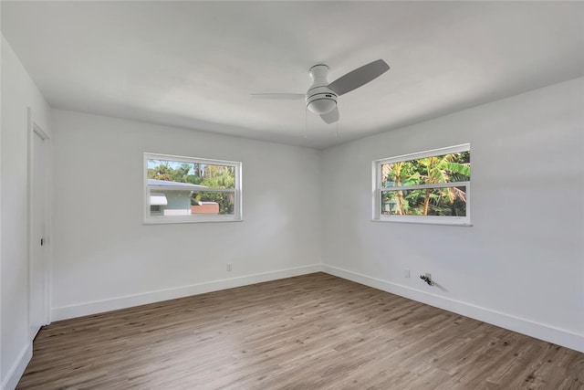 spare room with baseboards, ceiling fan, wood finished floors, and a healthy amount of sunlight