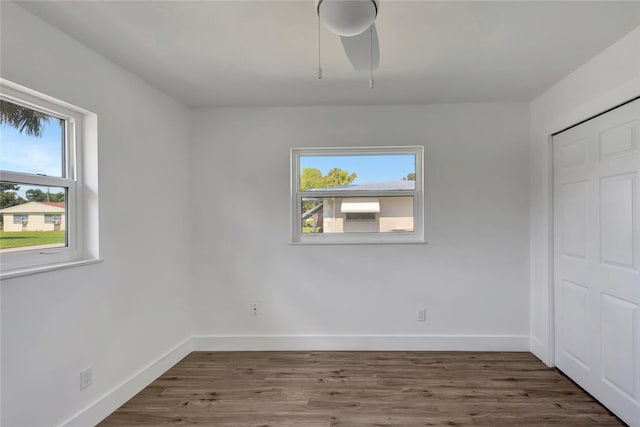 unfurnished bedroom with an AC wall unit, a closet, wood finished floors, and baseboards