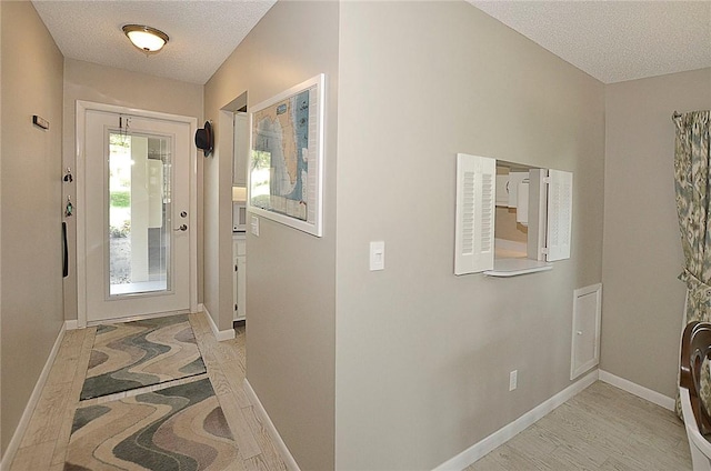 entrance foyer featuring light wood-style floors, a textured ceiling, and baseboards