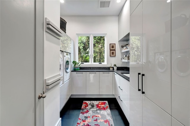 kitchen with dark tile patterned floors, white cabinets, washing machine and dryer, and white refrigerator