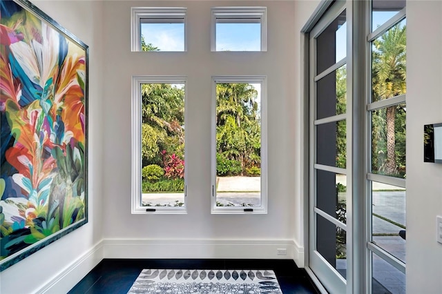 doorway with dark tile patterned floors and plenty of natural light