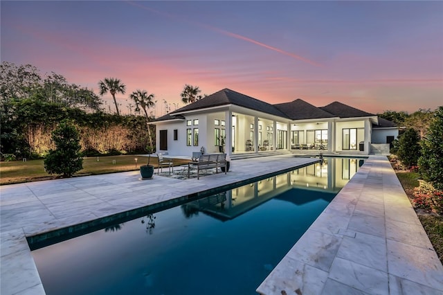 pool at dusk featuring a patio