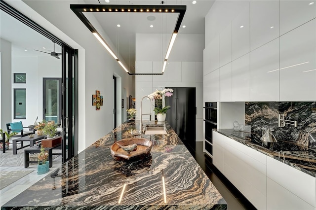 kitchen with white cabinetry, dark stone counters, and sink