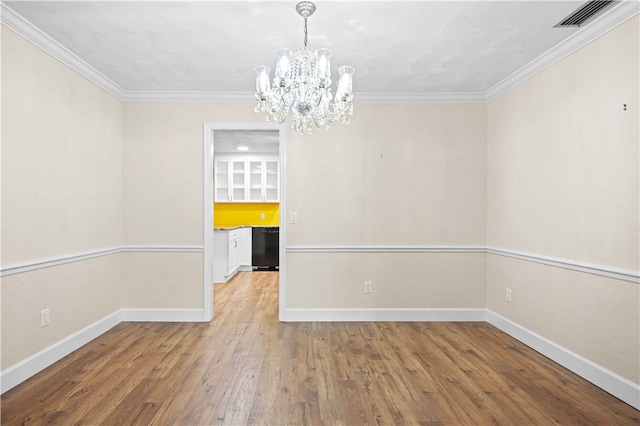 unfurnished dining area with visible vents, ornamental molding, wood finished floors, baseboards, and a chandelier