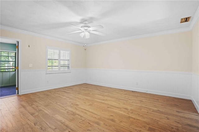 empty room featuring a wealth of natural light, visible vents, wainscoting, and light wood-type flooring