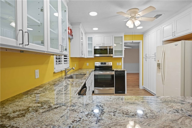 kitchen featuring light stone countertops, visible vents, a sink, stainless steel appliances, and white cabinets