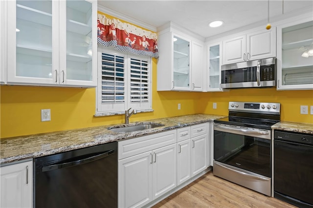 kitchen featuring white cabinets, appliances with stainless steel finishes, light wood-style flooring, and a sink