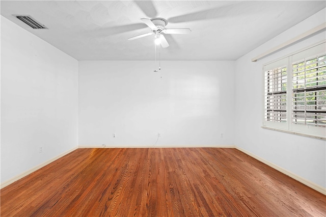 unfurnished room with visible vents, baseboards, wood finished floors, and a ceiling fan