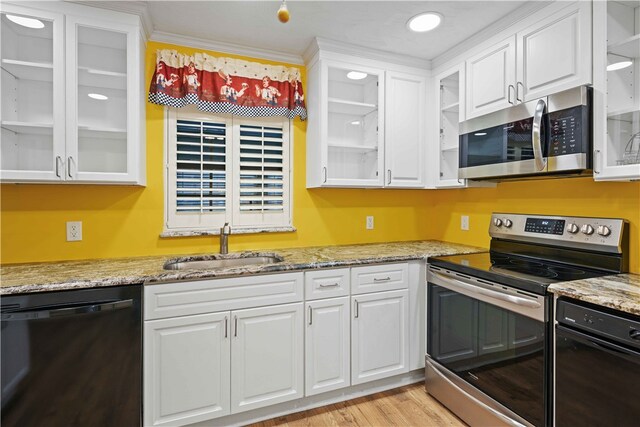 kitchen featuring light stone counters, white cabinets, appliances with stainless steel finishes, and a sink