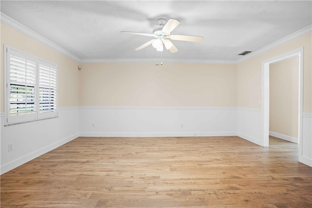 empty room featuring light wood-type flooring, visible vents, a ceiling fan, and crown molding