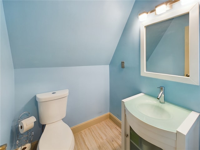 bathroom featuring lofted ceiling, vanity, wood-type flooring, and toilet