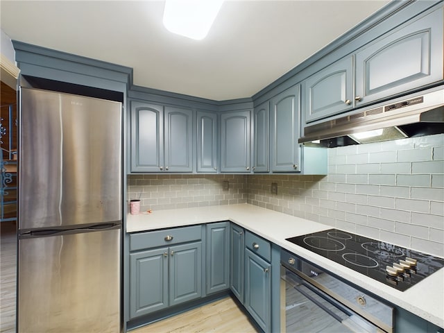 kitchen featuring tasteful backsplash, wall oven, light wood-type flooring, stainless steel fridge, and black electric stovetop