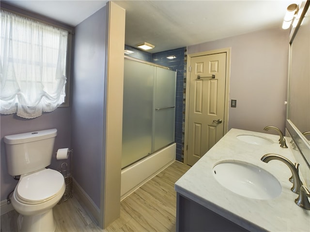 full bathroom with hardwood / wood-style flooring, enclosed tub / shower combo, vanity, and toilet