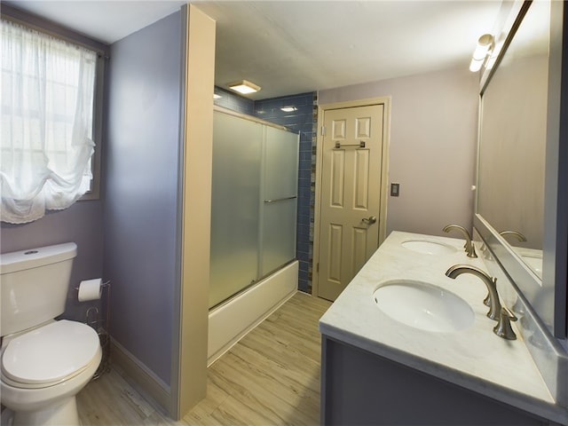 full bathroom featuring bath / shower combo with glass door, vanity, toilet, and hardwood / wood-style flooring