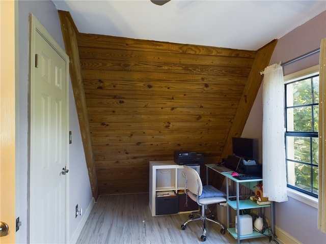 home office with wood-type flooring, vaulted ceiling, and wood walls