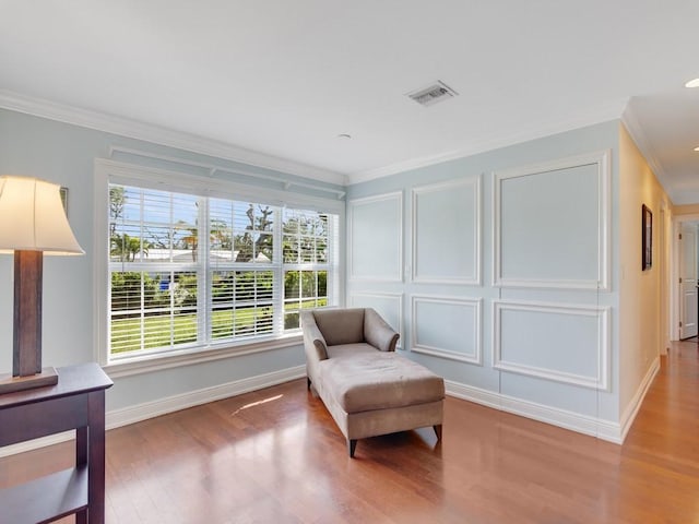 sitting room with wood-type flooring and ornamental molding