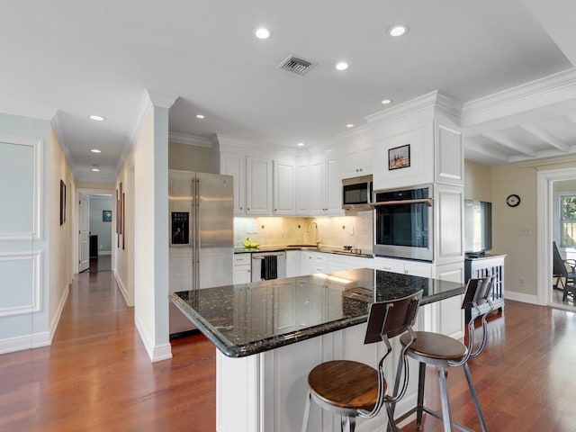 kitchen featuring white cabinetry, sink, dark stone countertops, a kitchen breakfast bar, and stainless steel appliances