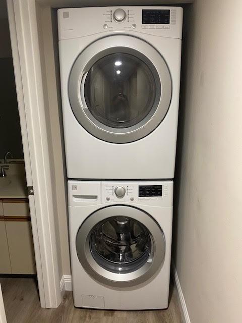 30 Plantation Dr Unit 104, Vero Beach, FL 32966 - laundry room featuring stacked washing machine and dryer, light wood-style flooring, and baseboards
