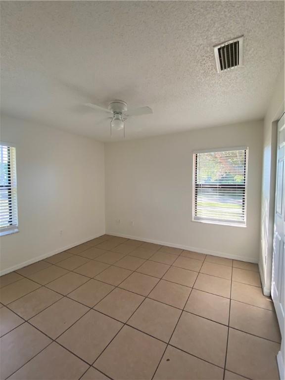 473 Englar Dr, Sebastian, FL 32958 - empty room featuring healthy amount of natural light, a textured ceiling, a ceiling fan, and light tile patterned floors