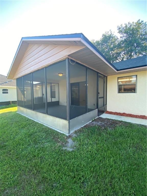473 Englar Dr, Sebastian, FL 32958 - rear view of house featuring a sunroom, a lawn, and stucco siding