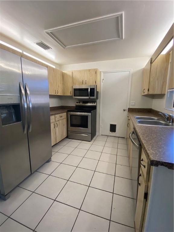 473 Englar Dr, Sebastian, FL 32958 - kitchen with appliances with stainless steel finishes, light brown cabinetry, dark countertops, and light tile patterned floors