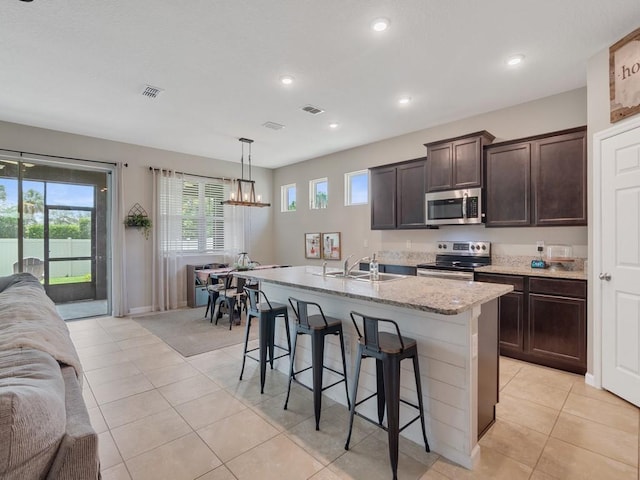 2641 Crowned Eagle Cir SW, Vero Beach, FL 32962 - kitchen featuring stainless steel appliances, dark brown cabinetry, open floor plan, a kitchen breakfast bar, and recessed lighting