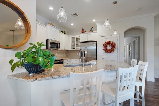 kitchen with appliances with stainless steel finishes, decorative light fixtures, white cabinetry, and sink