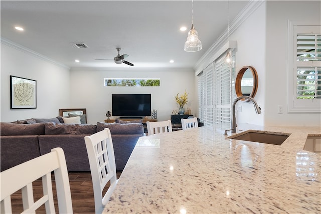 interior space with sink, hanging light fixtures, ceiling fan, a wealth of natural light, and light stone counters