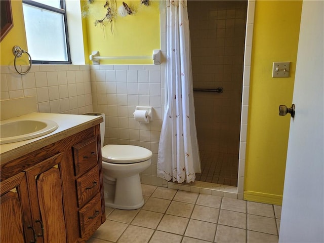 bathroom with tiled shower, vanity, tile patterned flooring, toilet, and tile walls