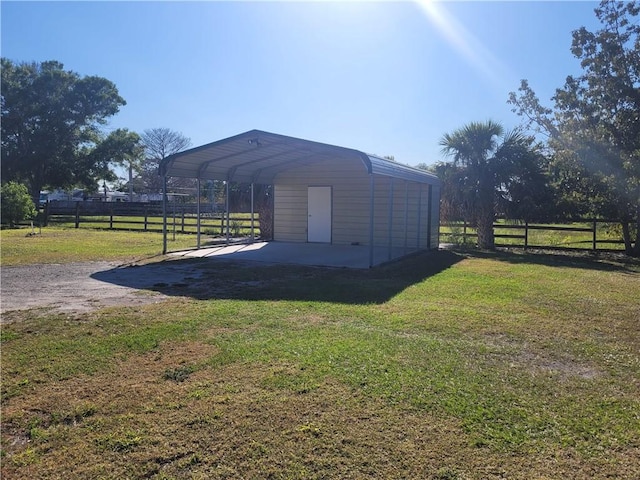 view of outbuilding with a carport, fence, and driveway