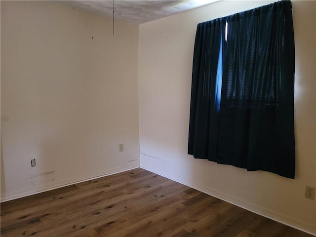 spare room with baseboards and wood finished floors