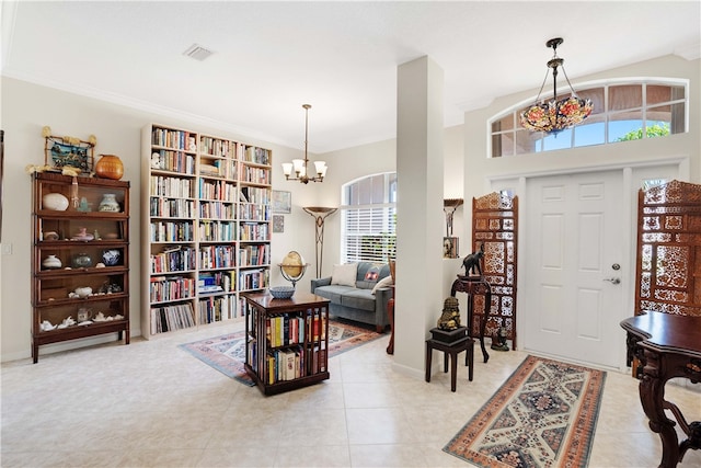 tiled foyer with crown molding and an inviting chandelier