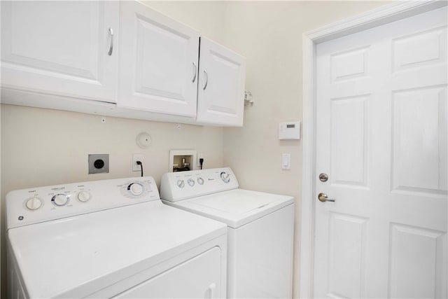 laundry room with washing machine and clothes dryer and cabinets