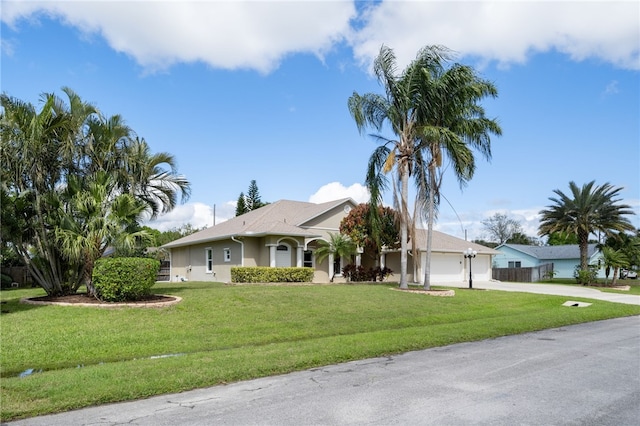 ranch-style home with driveway, an attached garage, fence, a front lawn, and stucco siding