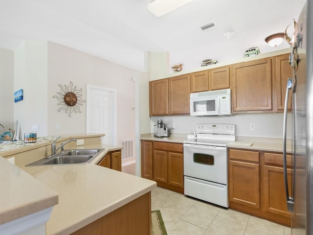 kitchen featuring light tile patterned flooring, white appliances, kitchen peninsula, and sink