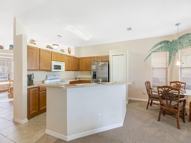 kitchen with pendant lighting, white appliances, a kitchen island, and light tile patterned floors