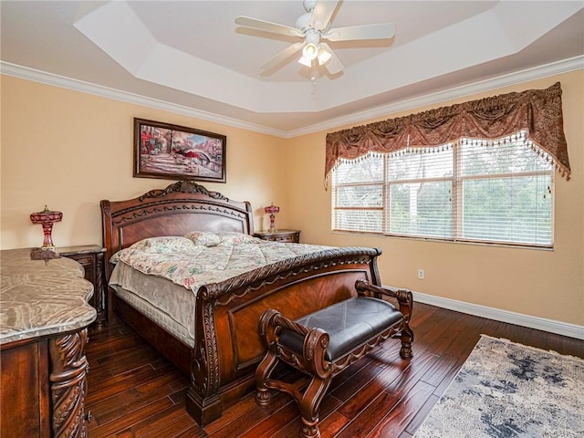 bedroom featuring dark hardwood / wood-style flooring, a tray ceiling, ceiling fan, and ornamental molding