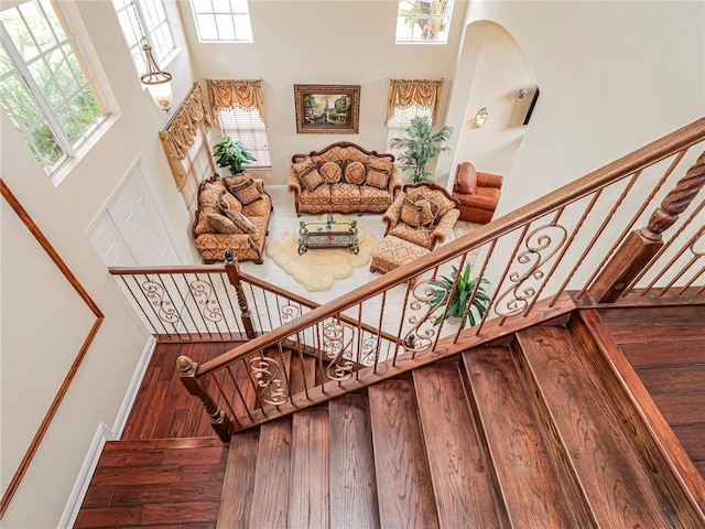 stairway with hardwood / wood-style flooring, a healthy amount of sunlight, and a high ceiling