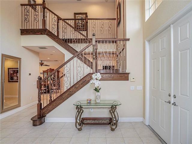 foyer with ceiling fan, tile patterned flooring, and a high ceiling