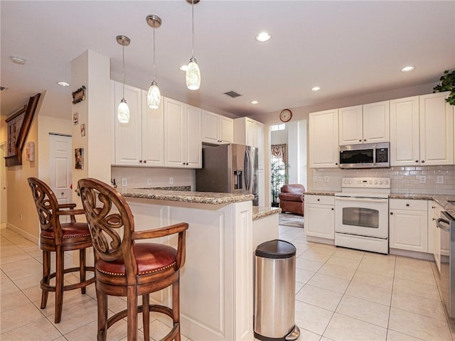 kitchen featuring pendant lighting, a breakfast bar, light stone countertops, appliances with stainless steel finishes, and white cabinetry