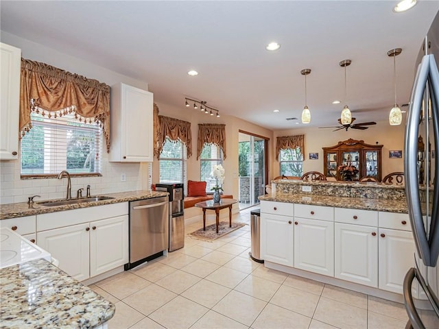 kitchen with plenty of natural light, white cabinetry, stainless steel appliances, and decorative light fixtures